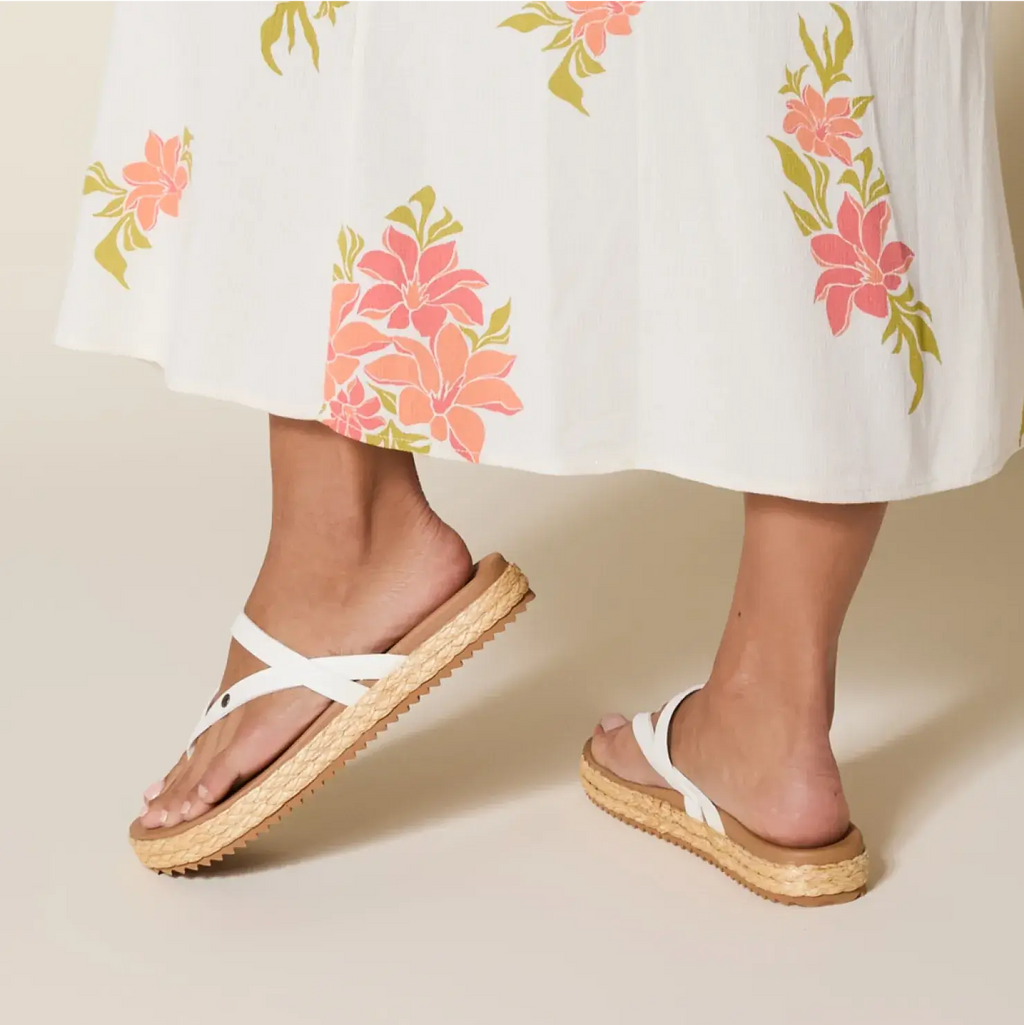 Vista Carmen sandals showing the left shoe from the side and heel with white straps and a woven sole, worn by a woman.