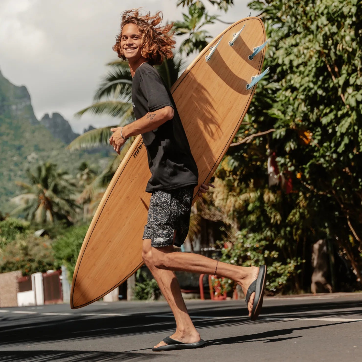 Man wearing Cruiser sandals facing right, walking outdoors with a surfboard, showcasing comfort and beach-ready style.