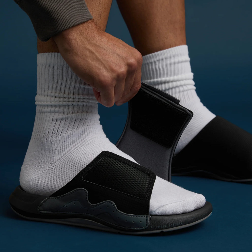 Close-up of a left-foot Cruiser Slide sandal facing right with adjustable strap, showing surf-inspired comfort features.