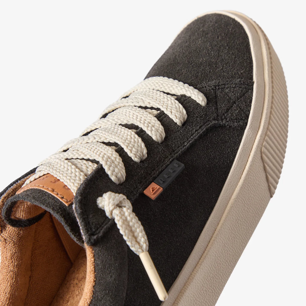 Close-up of the front and side of the Lay Day Dawn charcoal suede sneaker facing right, showing laces and arch support.