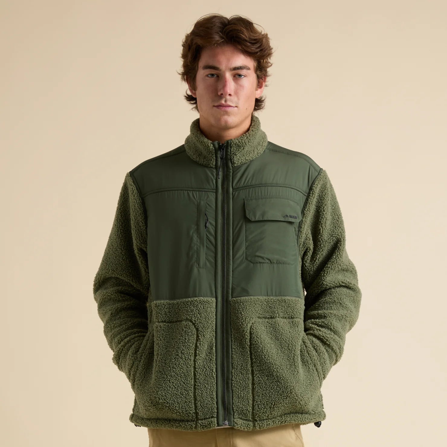 Front-facing view of a man wearing the Cooke Sherpa Jacket in olive green, showcasing comfort and beach-inspired style.