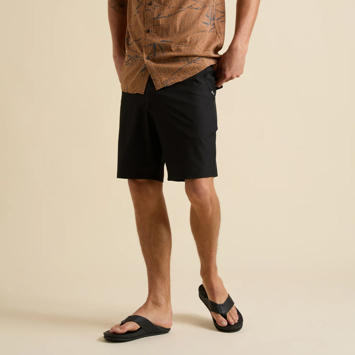 Man wearing black Dante Walk Short standing with feet forward in black REEF flip flop sandals designed for comfort and beach lifestyles
