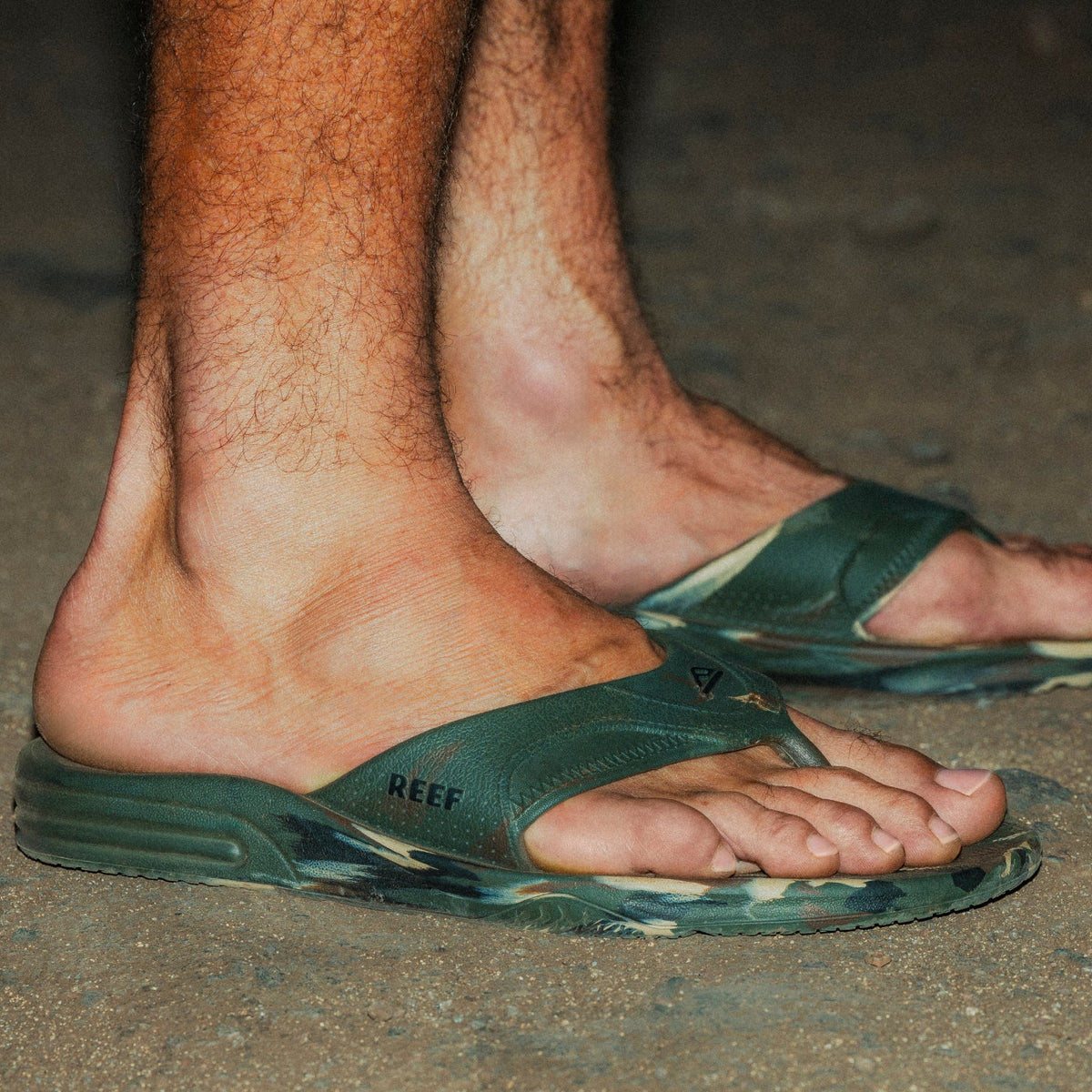 Side view of men's Fanning H2O flip flops in green, showing cushioned arch support and water-friendly sole on sand.