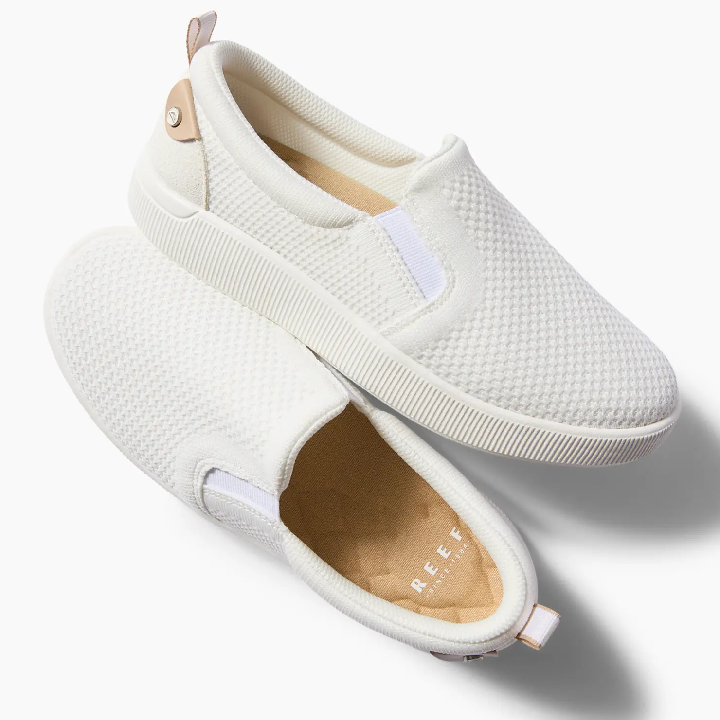 Pair of white Neptune Elyse slip-on sneakers for women showing top and right side, surf-inspired comfort footwear