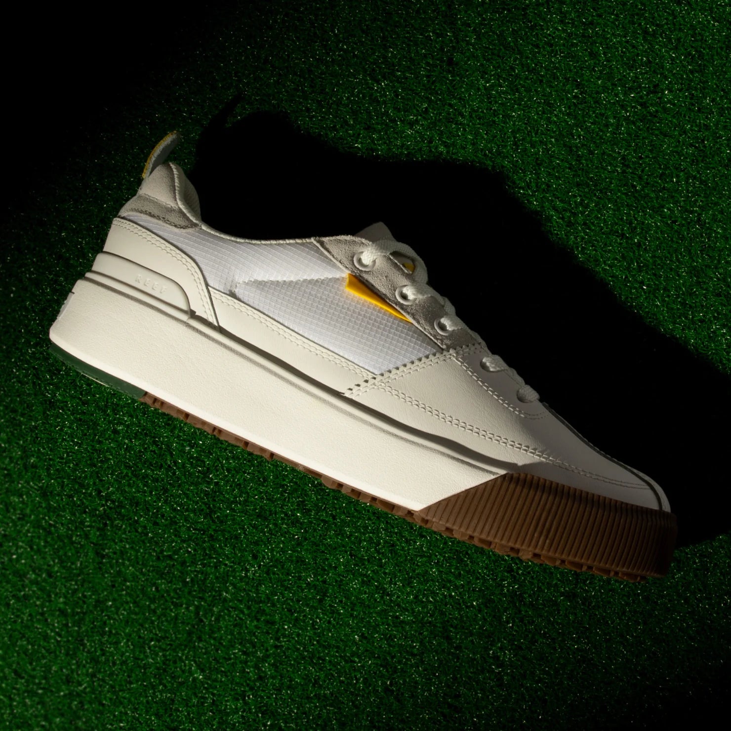 Onshore Pines men's white sneaker left side profile, lightweight and comfort-focused with gum sole on green surface.