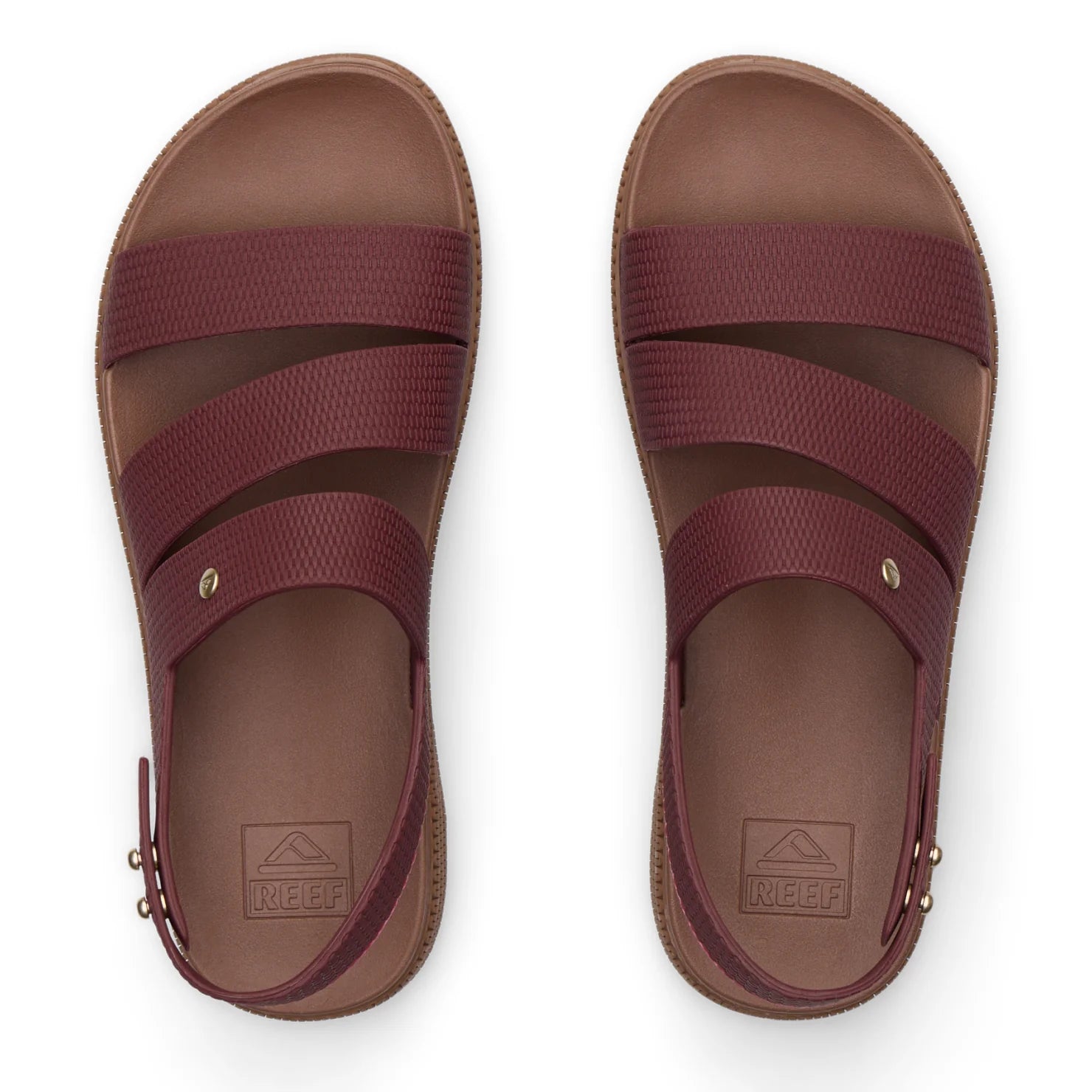 Top view of maroon REEF sandals with three straps and molded footbeds, designed for beach comfort and durability.