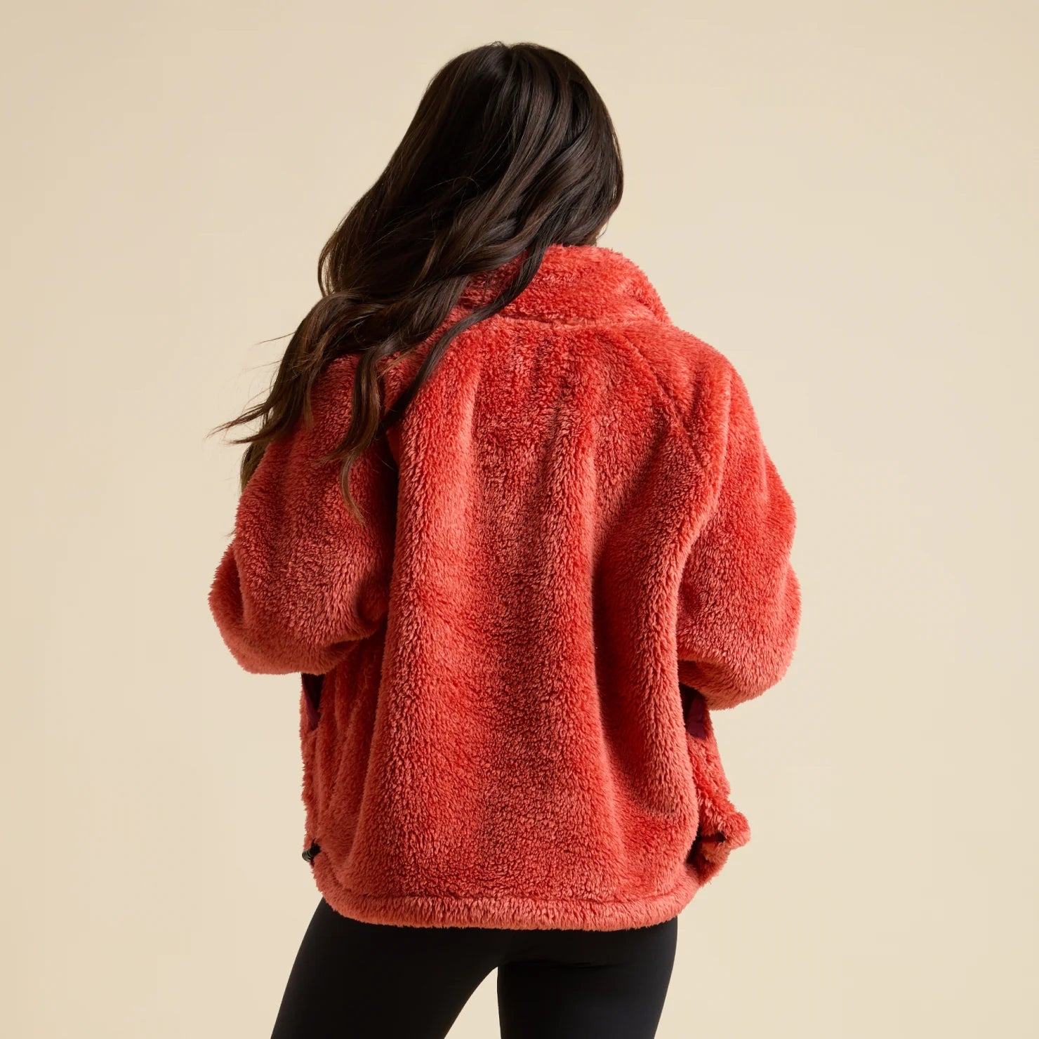 Woman wearing a red Pilot Sherpa Jacket from the back, showcasing its soft, comfortable, surf-inspired apparel design.