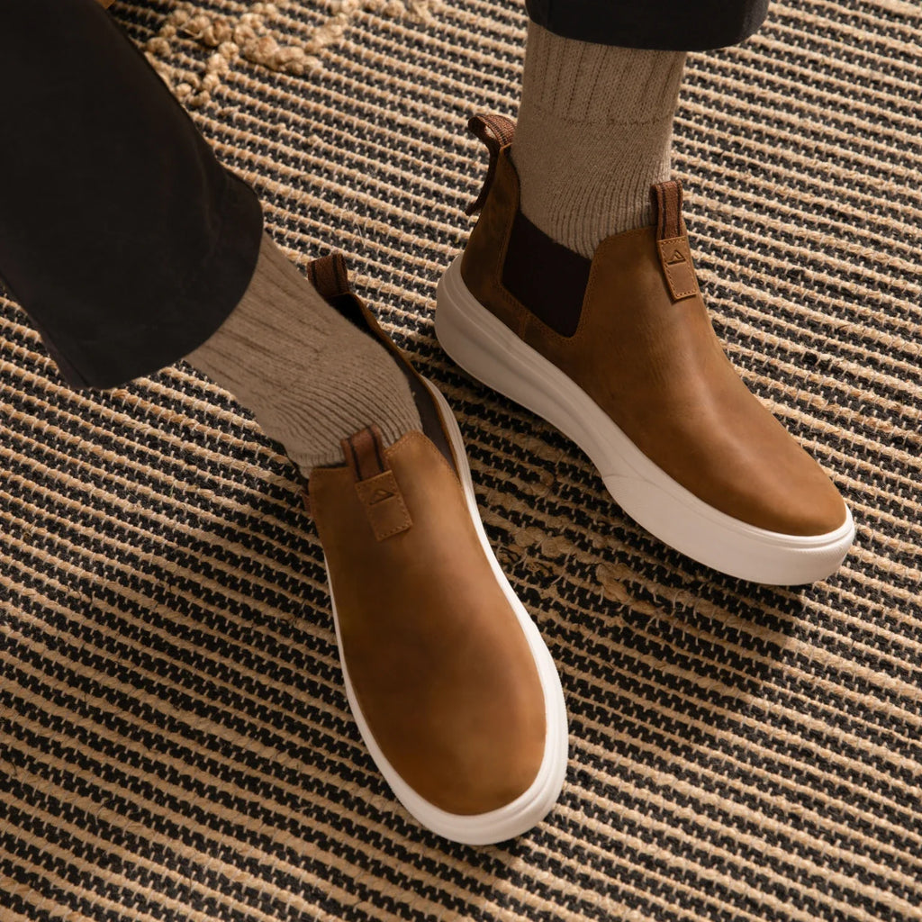 Evo brown men's slip-on shoes facing forward with soft-rebound cushioning and anatomical arch support on a woven rug.