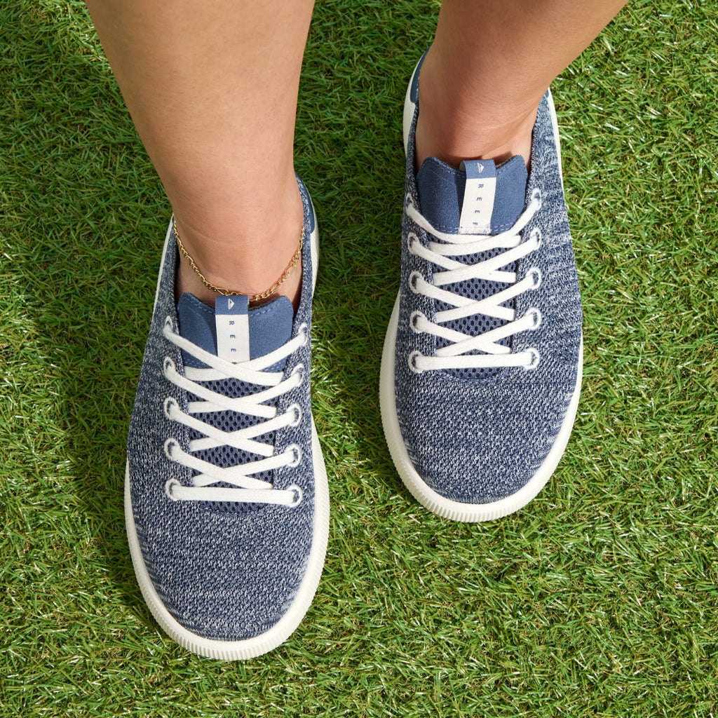 Top-down view of women's Reef Neptune sneakers facing forward on grass, featuring comfort and water-friendly materials.