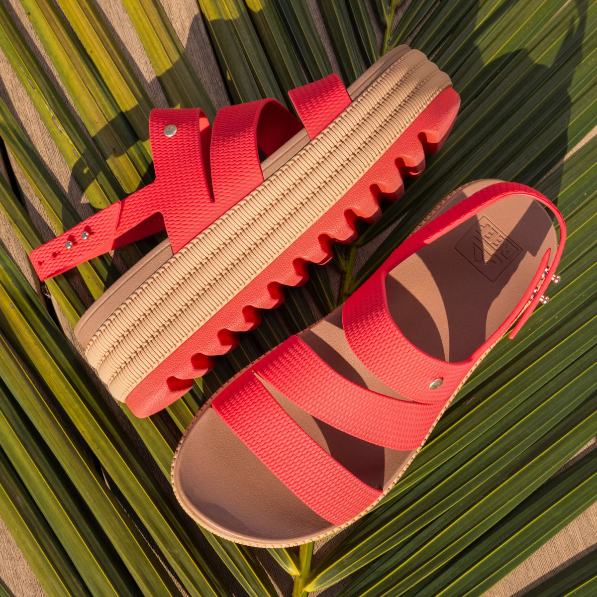 Water Vista Higher 2 women's sandals facing right with red straps, ridged platform sole, and cushioned footbed on palm leaf.