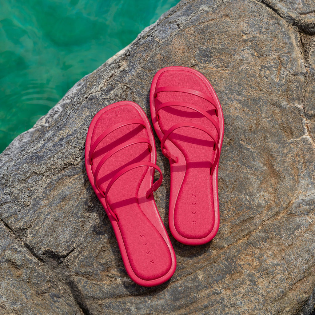Willow Ava-Rose women's red sandals viewed from above showing straps and cushioned footbed on rock by water.