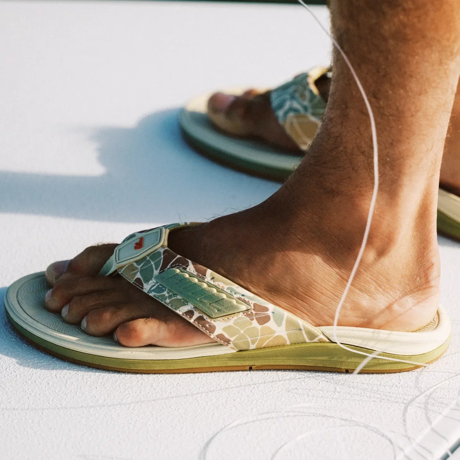 Free Fly X Offshore men's sandal facing left, green camo strap with fly fishing patch, cushioned sole, water-friendly comfort