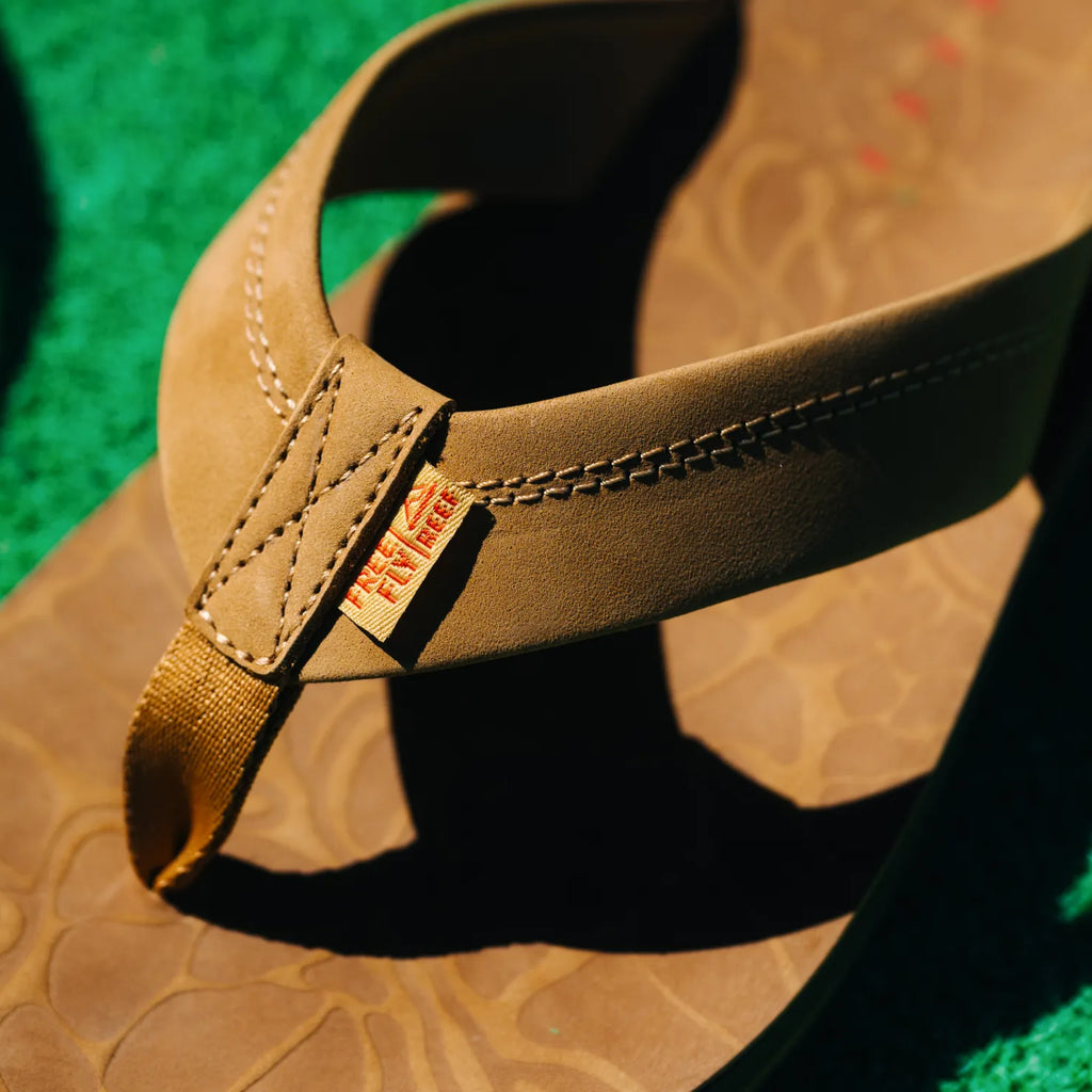 Free Fly X Ojai men's brown leather sandal close-up on toe post and strap stitching with water-friendly footbed texture facing forward
