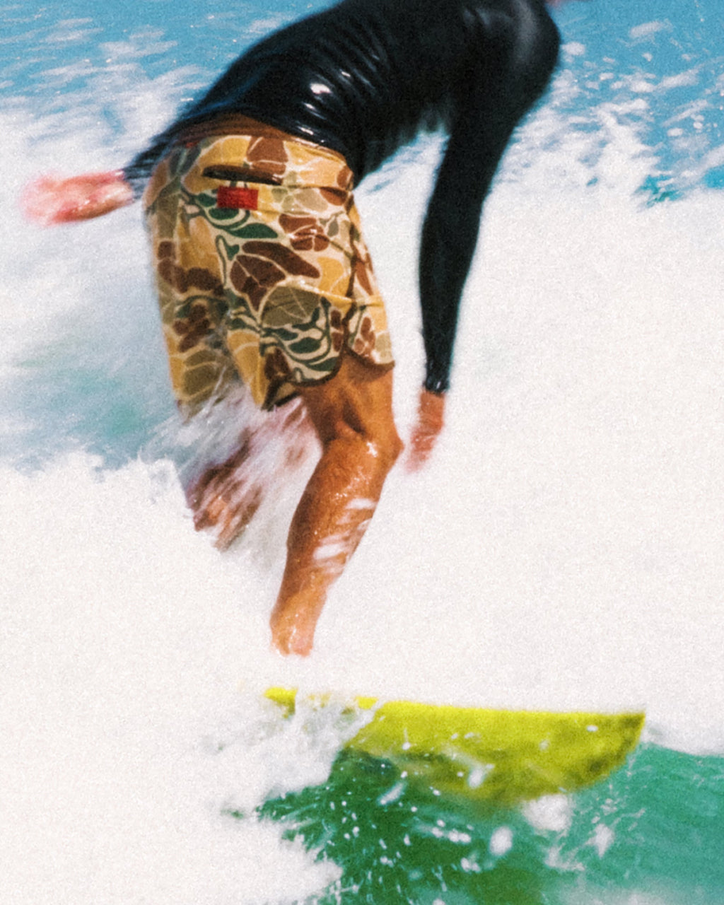 Man surfing wearing Men's Palmera Boardshort - Floral Camo with water splashing, beach-inspired activewear for comfort and durability