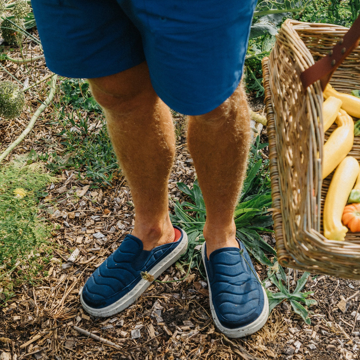 Rambler Kicker navy slip on shoes facing forward with cushioned comfort in a garden setting