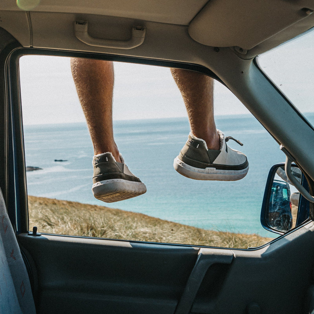 Rambler shoes viewed from behind with toes facing right above a coastal beach