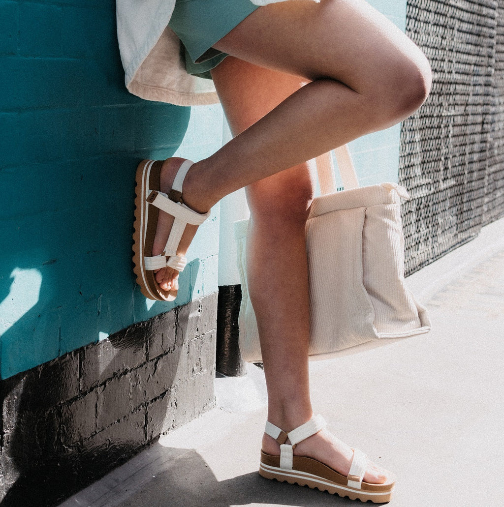 woman leaning up against brick wall with platform sandals