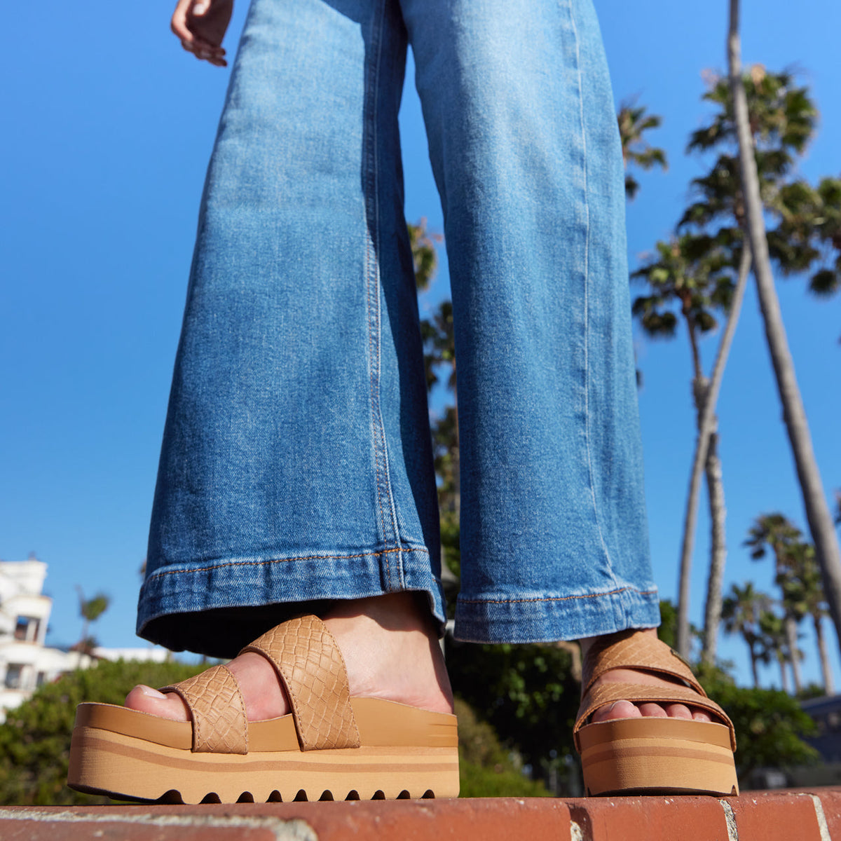 Cushion Vista Hi women's tan platform sandals facing forward, showing front straps and sole with beach background.