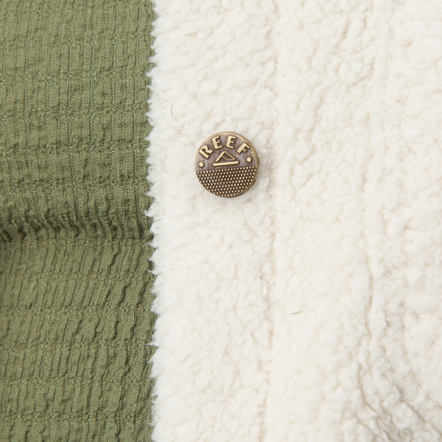 Close-up of the Sammie Sherpa Jacket showing the green fabric and cream sherpa with a branded REEF button detail.