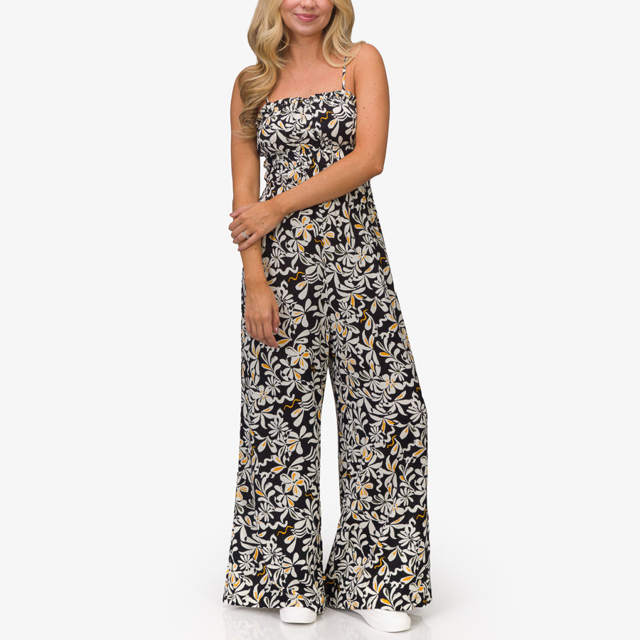 Woman wearing black floral Sandy Romper standing front view with relaxed fit and lightweight fabric, beach-inspired comfort.