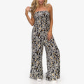 Woman wearing Sandy Romper in black floral print, standing front view, showcasing beach-inspired, comfortable apparel.