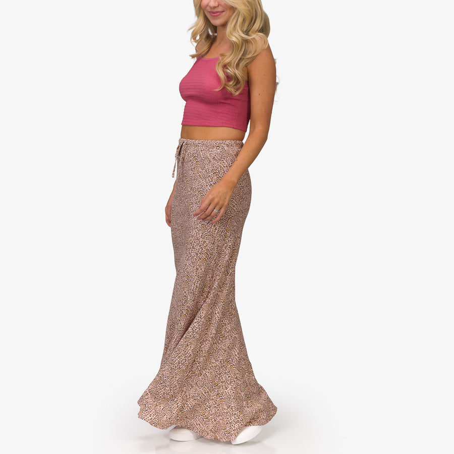 Woman wearing a patterned Sandy Maxi Skirt standing sideways, showcasing the full length and flow of the skirt.
