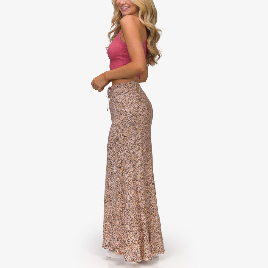 Woman wearing a patterned Sandy Maxi Skirt standing turned right, showcasing the skirt’s full length and fit from the side.