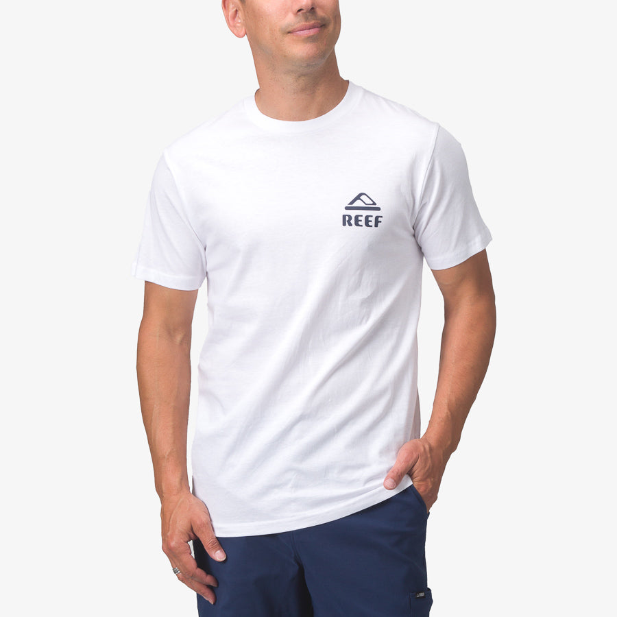 Front view of a man wearing a white Seafan Tee with a small Reef logo, styled for beach comfort and casual wear.