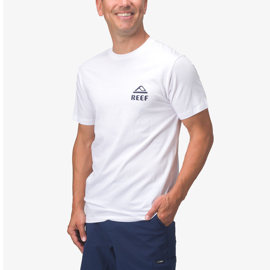 Front view of man wearing white Seafan Tee with small logo on chest, styled for beach comfort and active lifestyles.