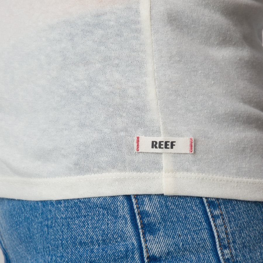 Close-up of the bottom hem of the white Surf Club Fitted Tee showing the REEF label on lightweight, breathable apparel.