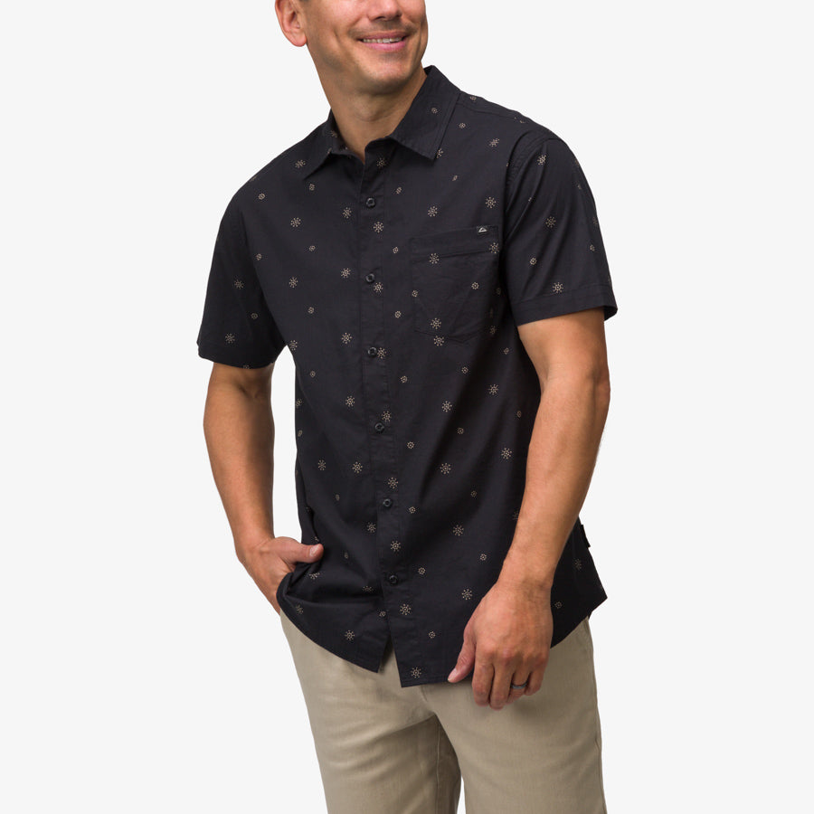 Man wearing a black Topaz Shirt with subtle patterns, standing with hands in pockets, beach-inspired comfort apparel.