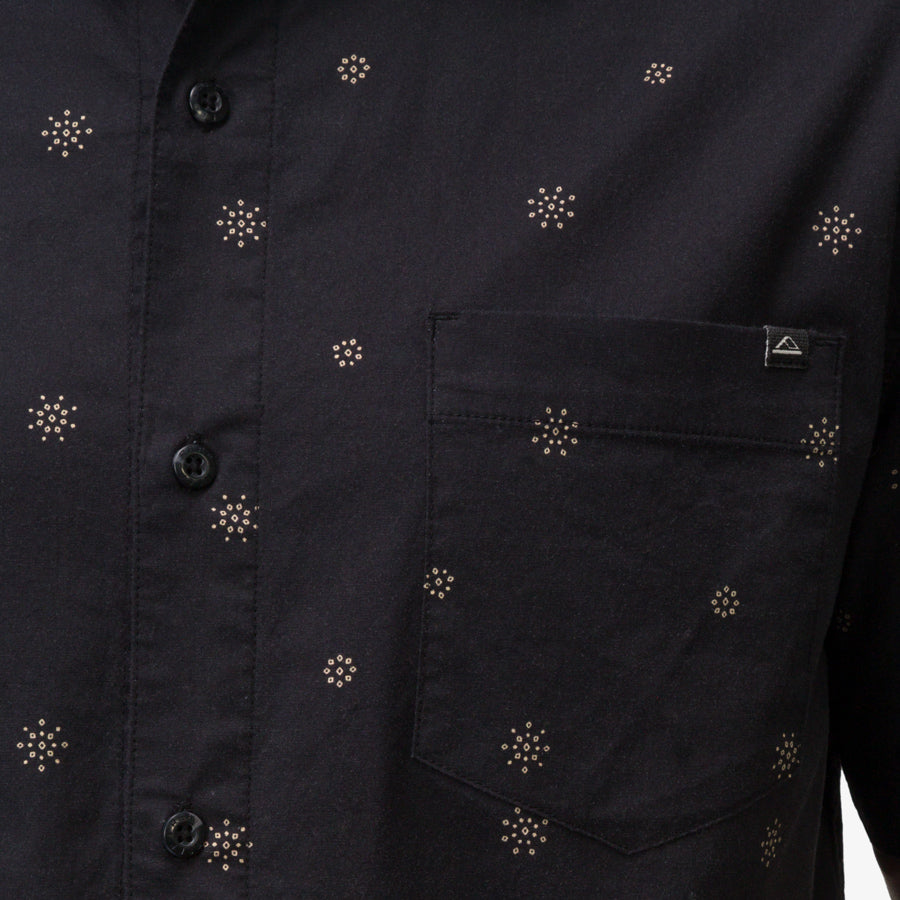 Close-up of the pocket and button area on the men's Topaz Shirt featuring subtle patterned dots on black fabric.