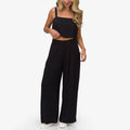 Woman wearing black Tori Linen Pant standing front view, showing full length and relaxed fit, paired with black crop top and white shoes.