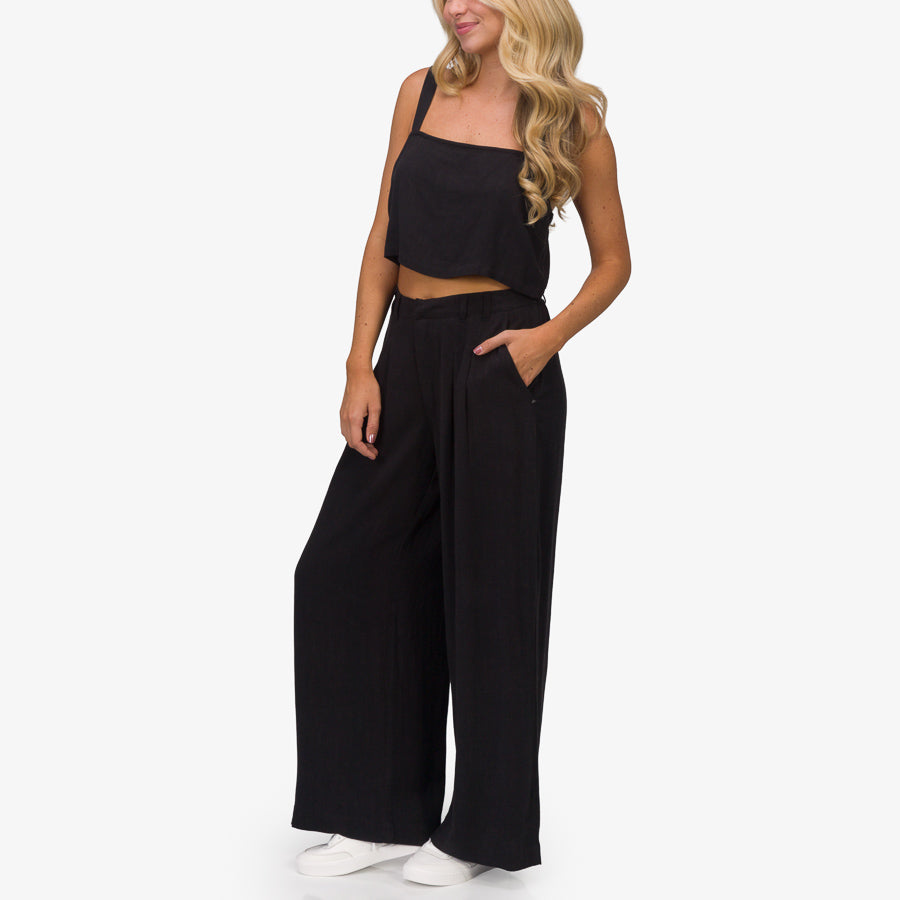 Woman wearing black Tori Linen Pant standing facing forward, showing relaxed fit and side pocket with casual comfort style.