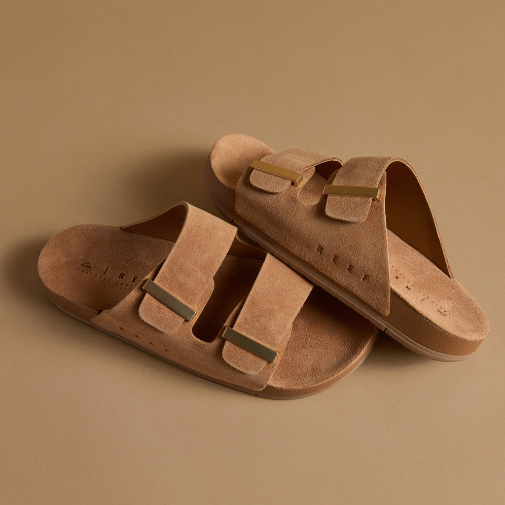 Ojai Two Bar sandals angled left, tan suede with dual straps, molded footbed, and comfort arch support by REEF.