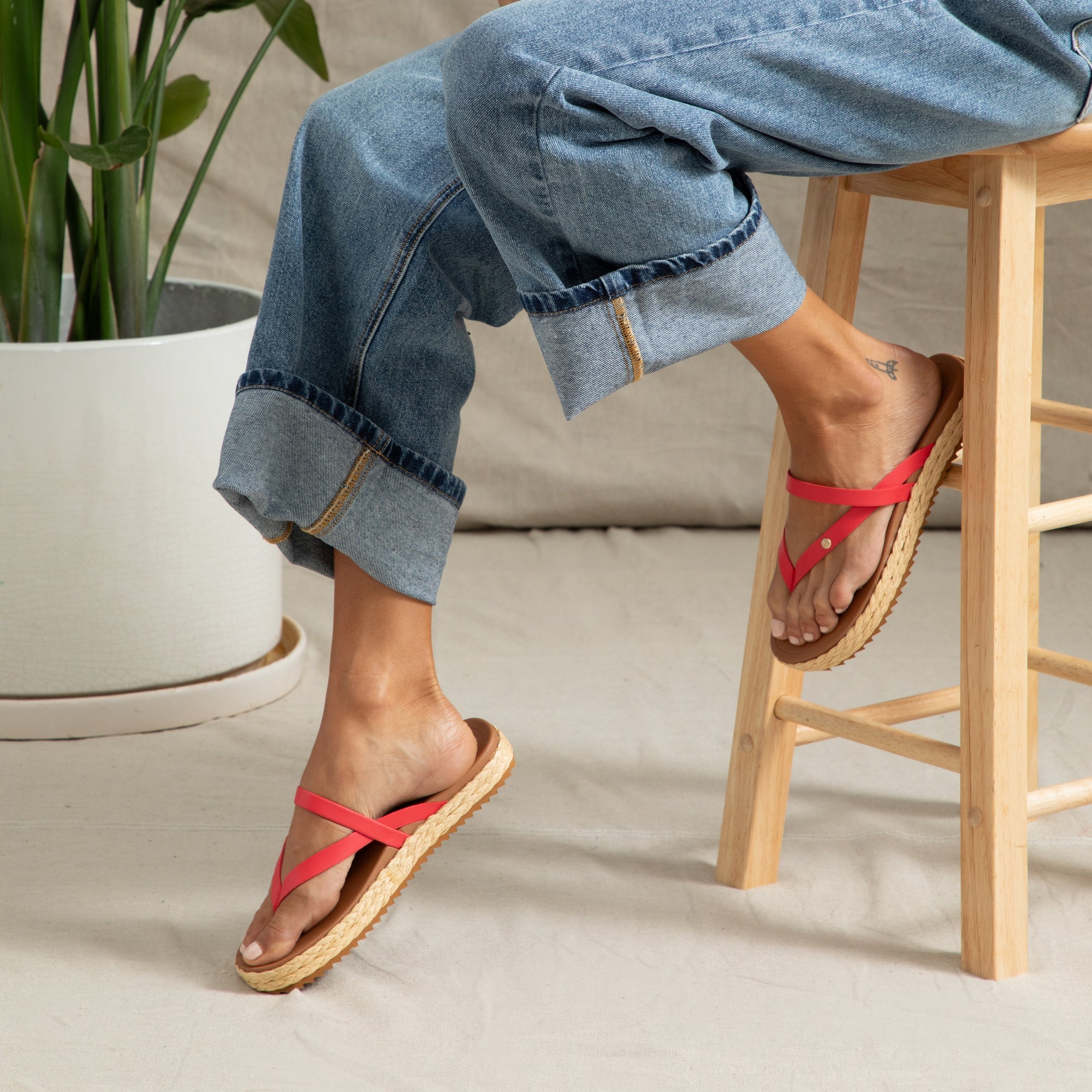 Vista Carmen women’s sandals facing left, showing red straps and cushioned footbed in a casual seated setting.