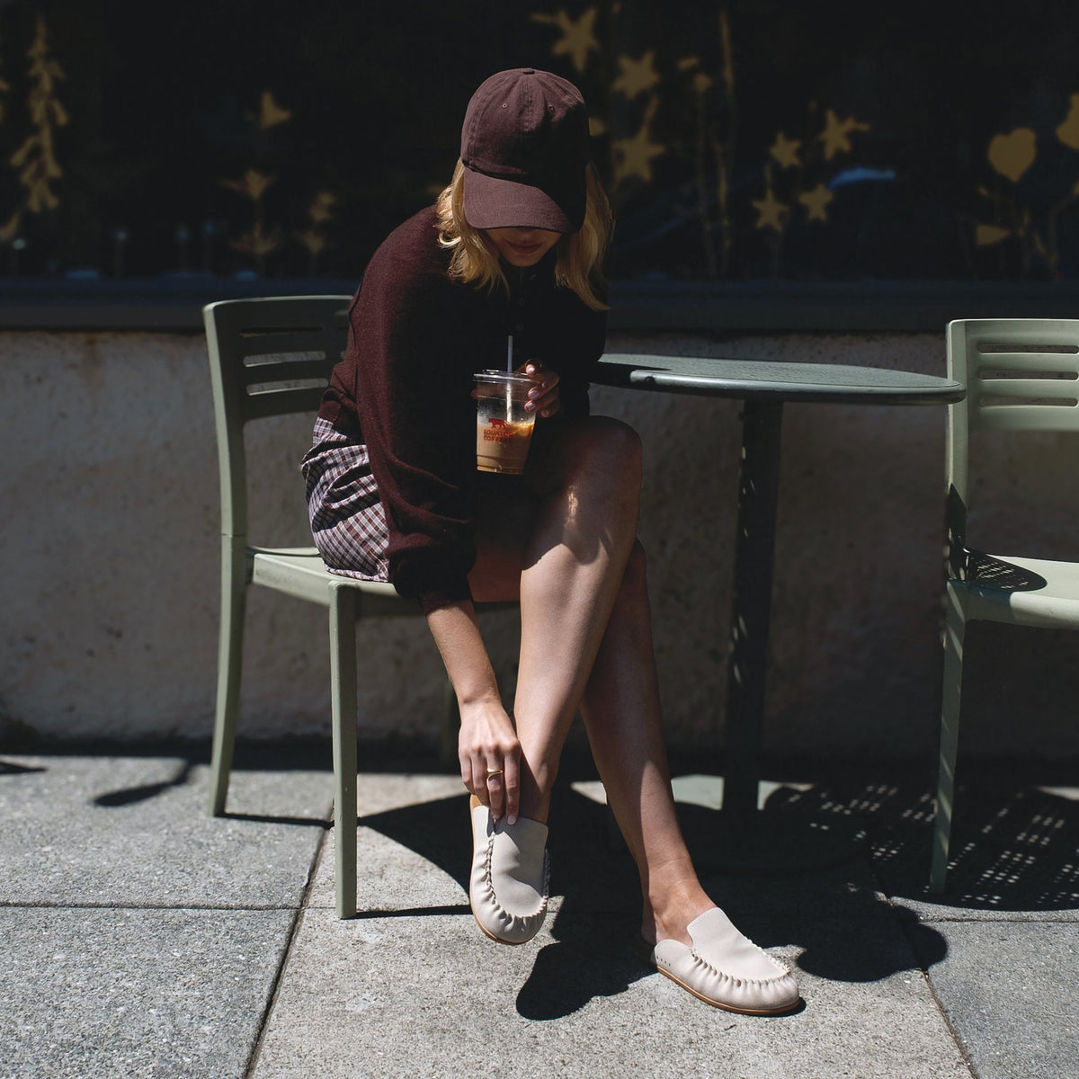 Woman seated outdoors wearing Vista Myra facing left, women's warm sand leather clog with enhanced arch support and soft cushioning