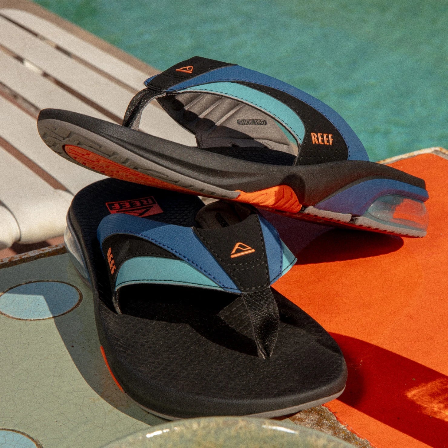 Fanning + men's black and blue sandals facing right with arch support and cushioned footbed, surf-inspired comfort design.