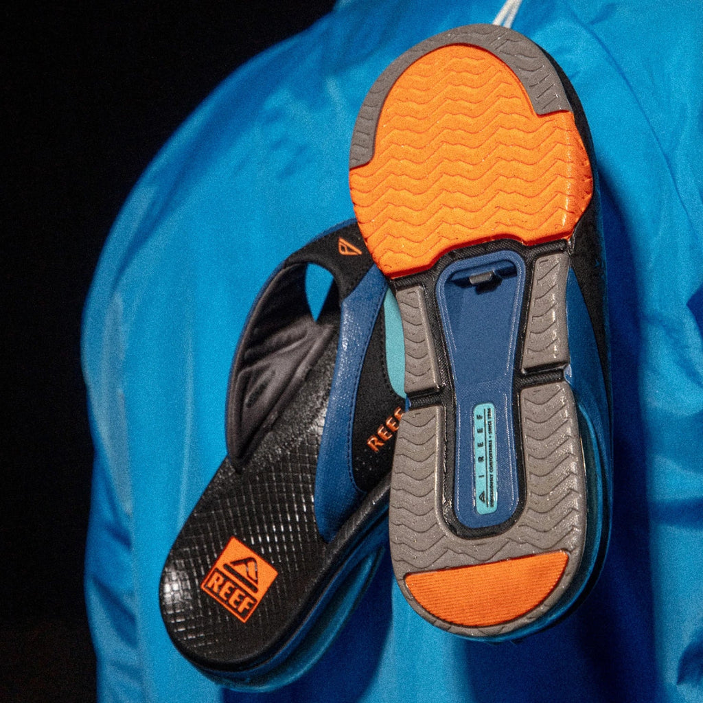 Fanning + men’s sandal showing vibrant orange sole facing forward with blue and black upper for beach comfort.